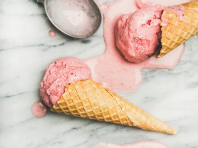 Healthy low calorie summer dessert. Homemade strawberry yogurt ice cream in sweet waffle cones on over grey marble table background, top view, close-up. Clean eating, dieting food concept